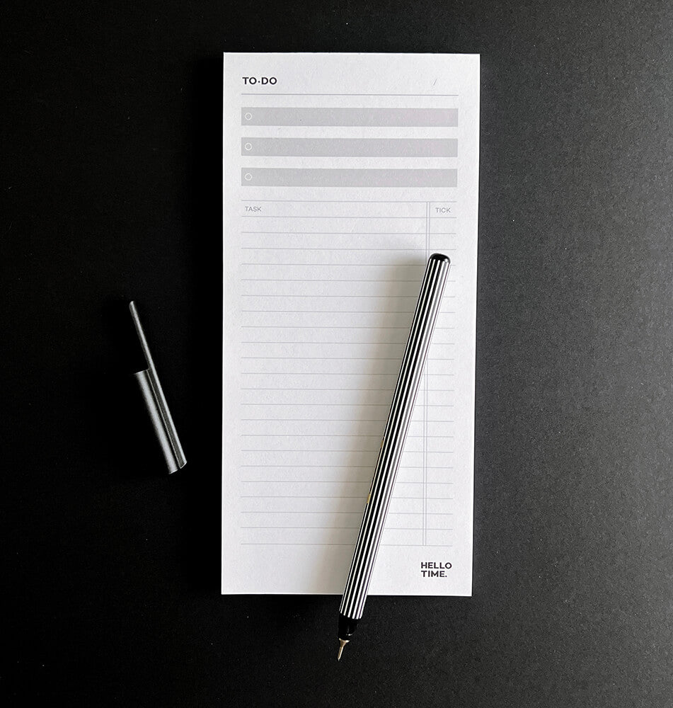 HELLO TIME Top 3 To-Do List Pad with black and white striped pen on black background