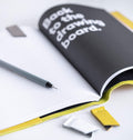HELLO TIME yellow leather notebook cover open with page being turned to reveal “Back to the drawing board” quote