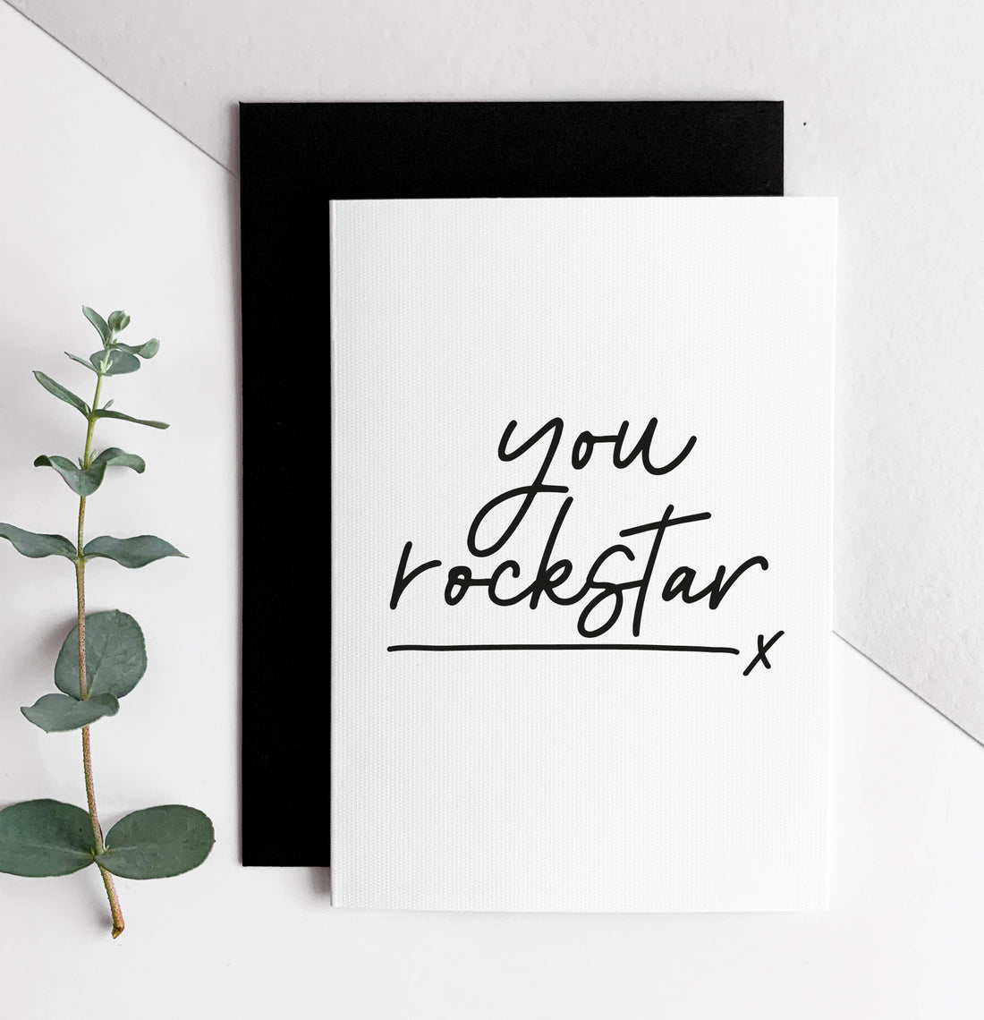 White card with black handwritten text “you rockstar” and black envelope, minimalist design.