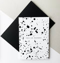 Black and white greeting card with splatter design and text “You’ve Passed,” paired with black envelope.