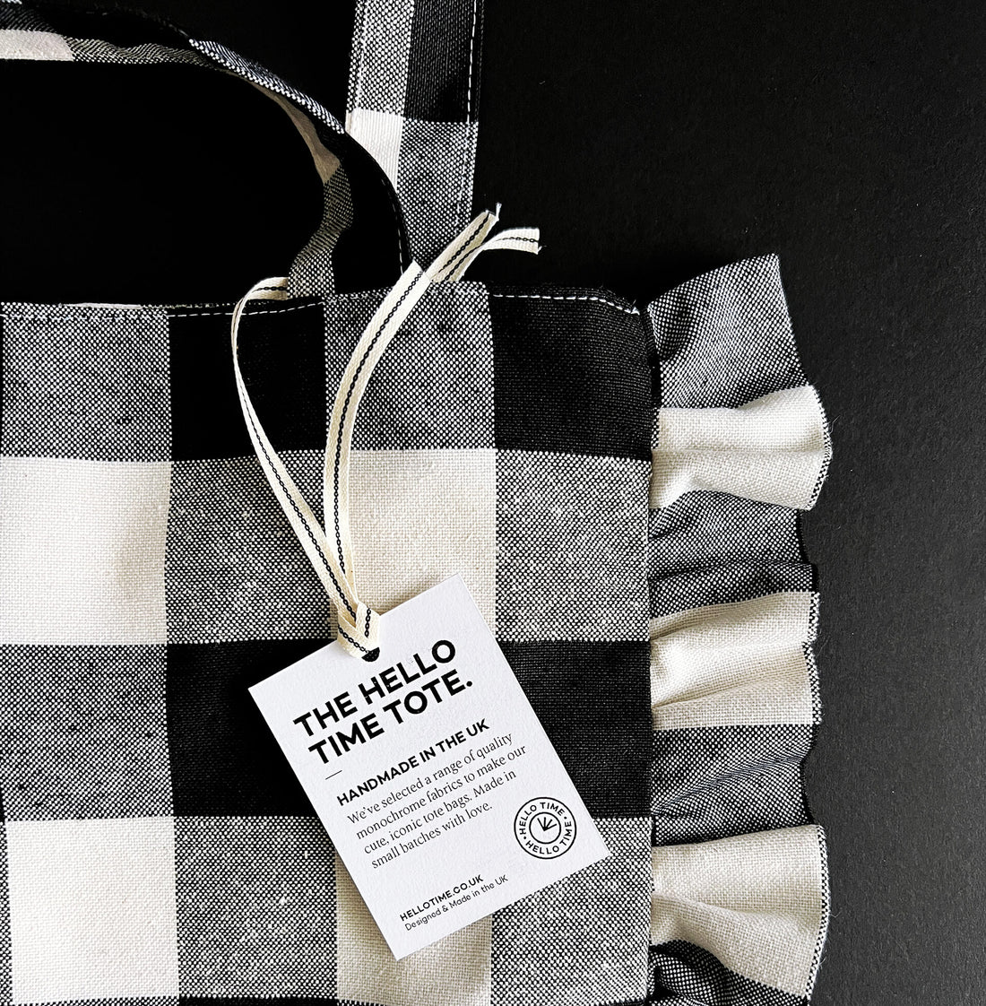 Black and white gingham ruffle tote bag with handles and product tag