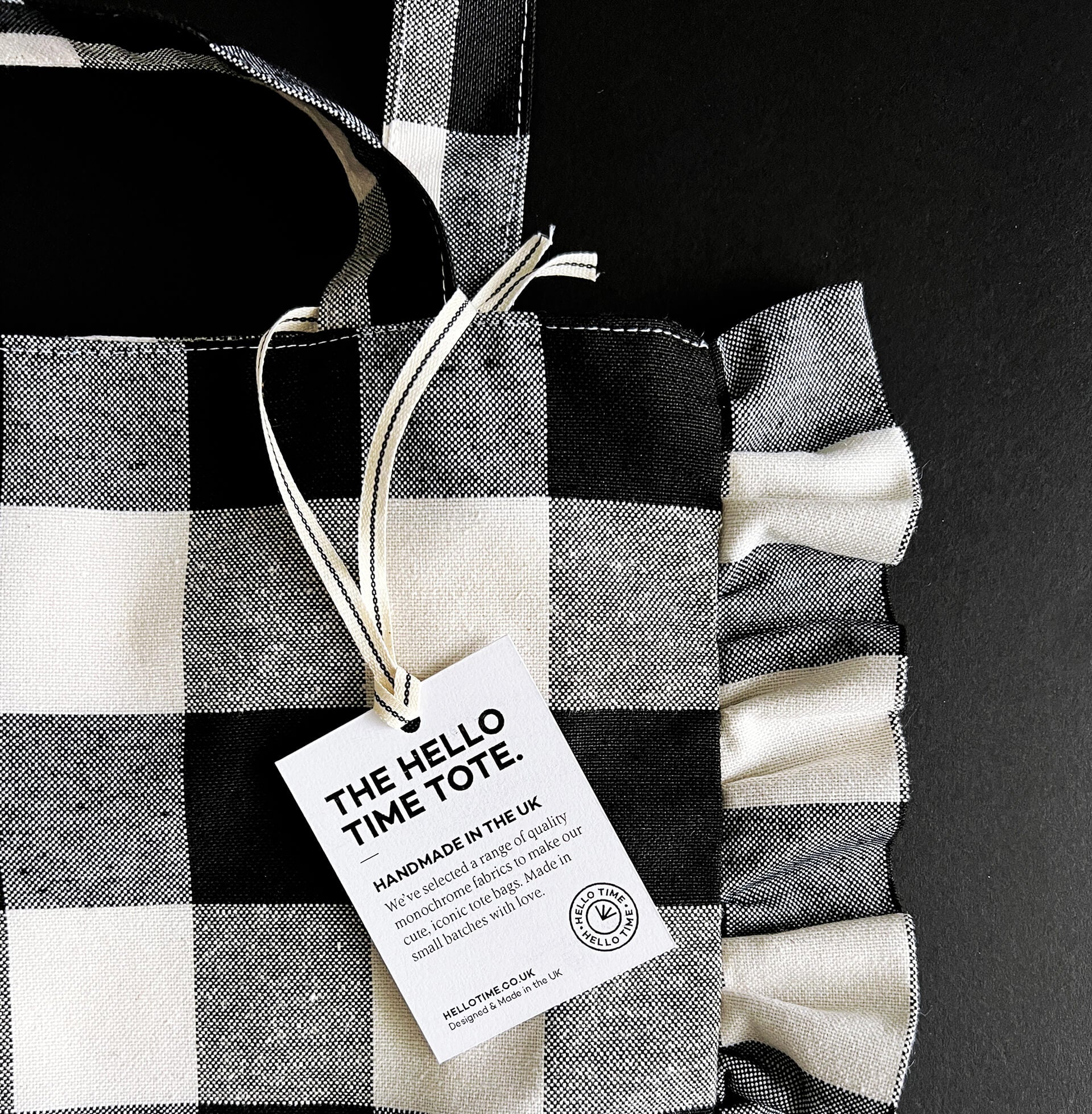 Black and white check tote bag with ruffled edges and Hello Time label