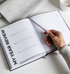 Hand holding HELLO TIME Planner open to the My Year Review reflection page